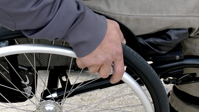 closeup of a person in a manual wheelchair, the person's hand on the wheel.
