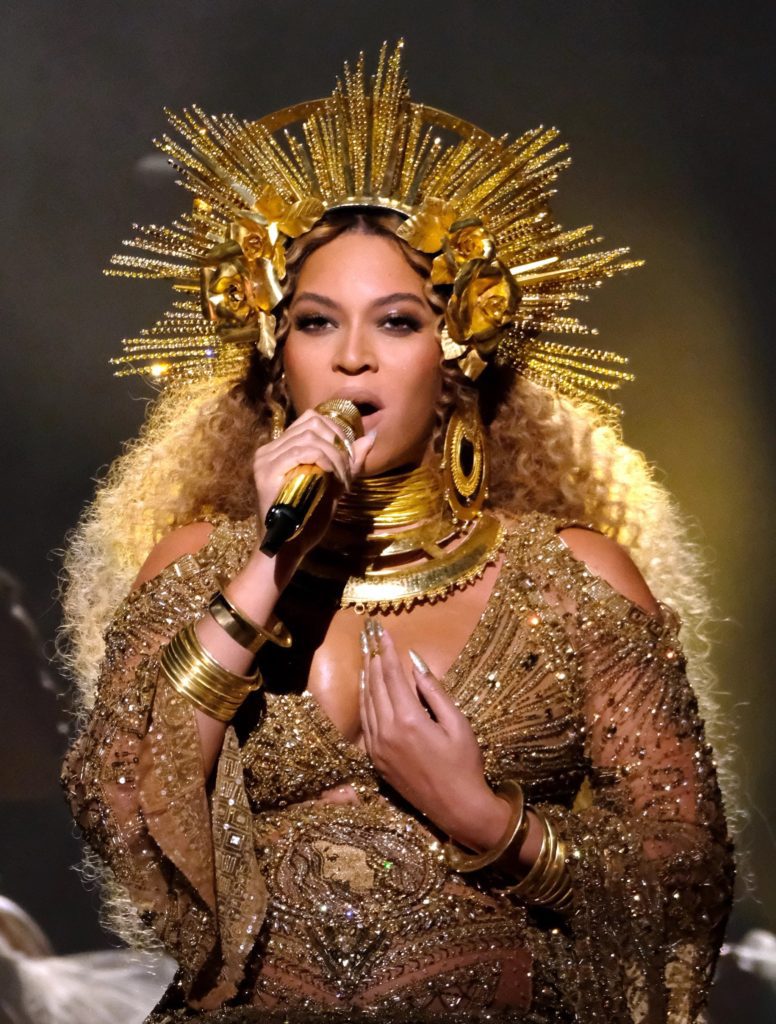 Beyoncé in concert, wearing a golden crown that radiates outward like a halo